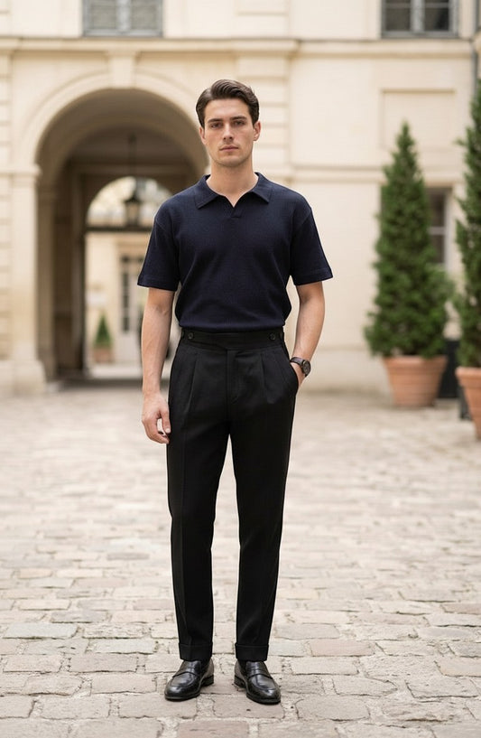 RADIUS model wearing black pleated Gurkha trousers with a navy polo shirt in a classic European courtyard setting.