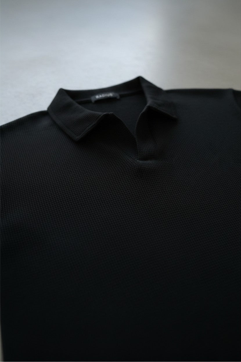RADIUS black waffle-knit polo shirt with a minimalist placket-less V-neck and integrated collar.