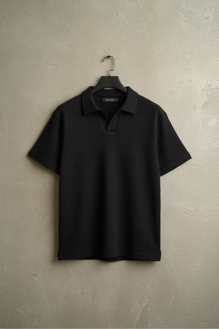 RADIUS black waffle-knit polo shirt with a minimalist placket-less V-neck and integrated collar on a hanger.