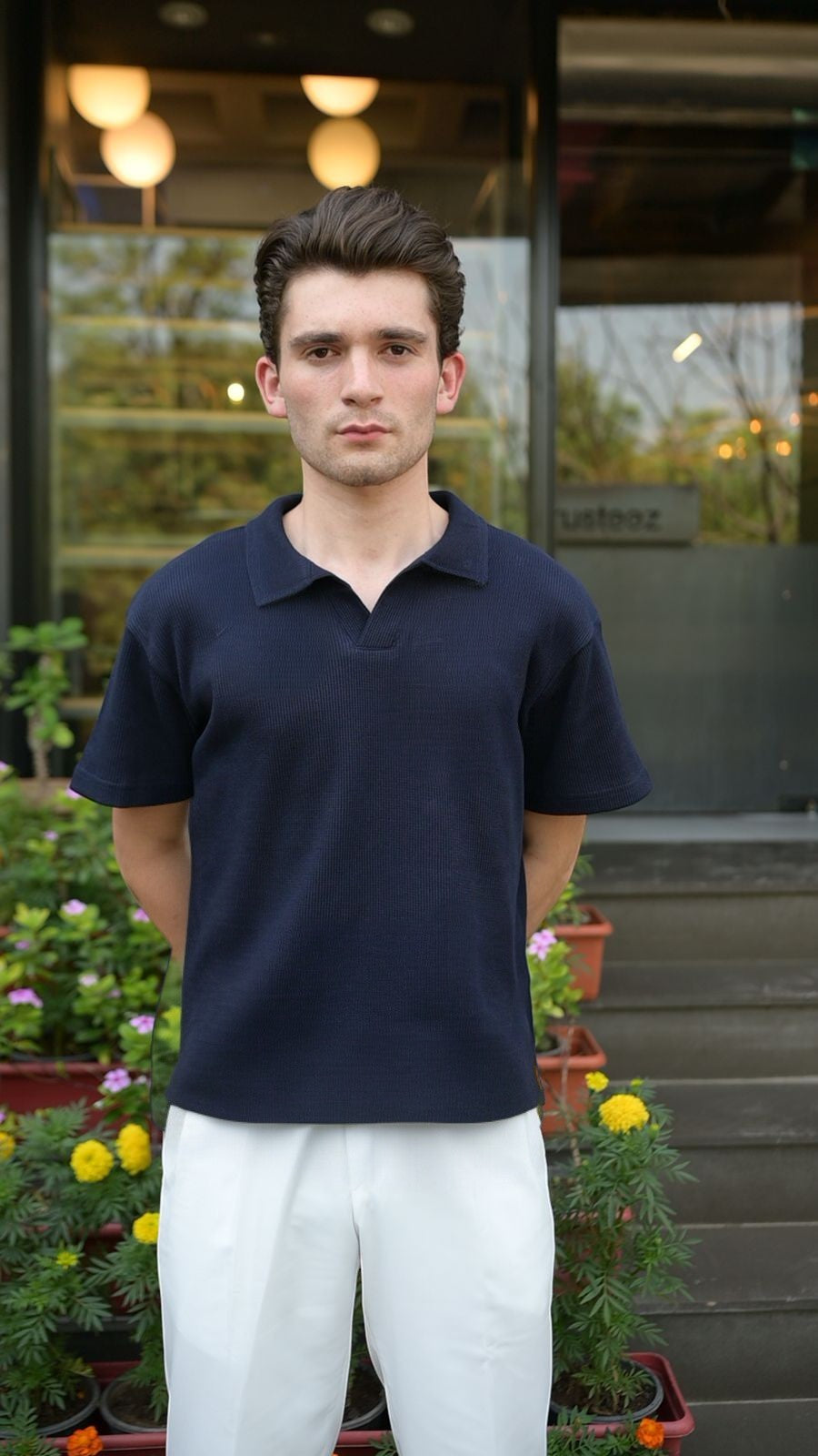 RADIUS midnight navy waffle-knit polo shirt with a V-neck and collar worn by a man with white trousers.