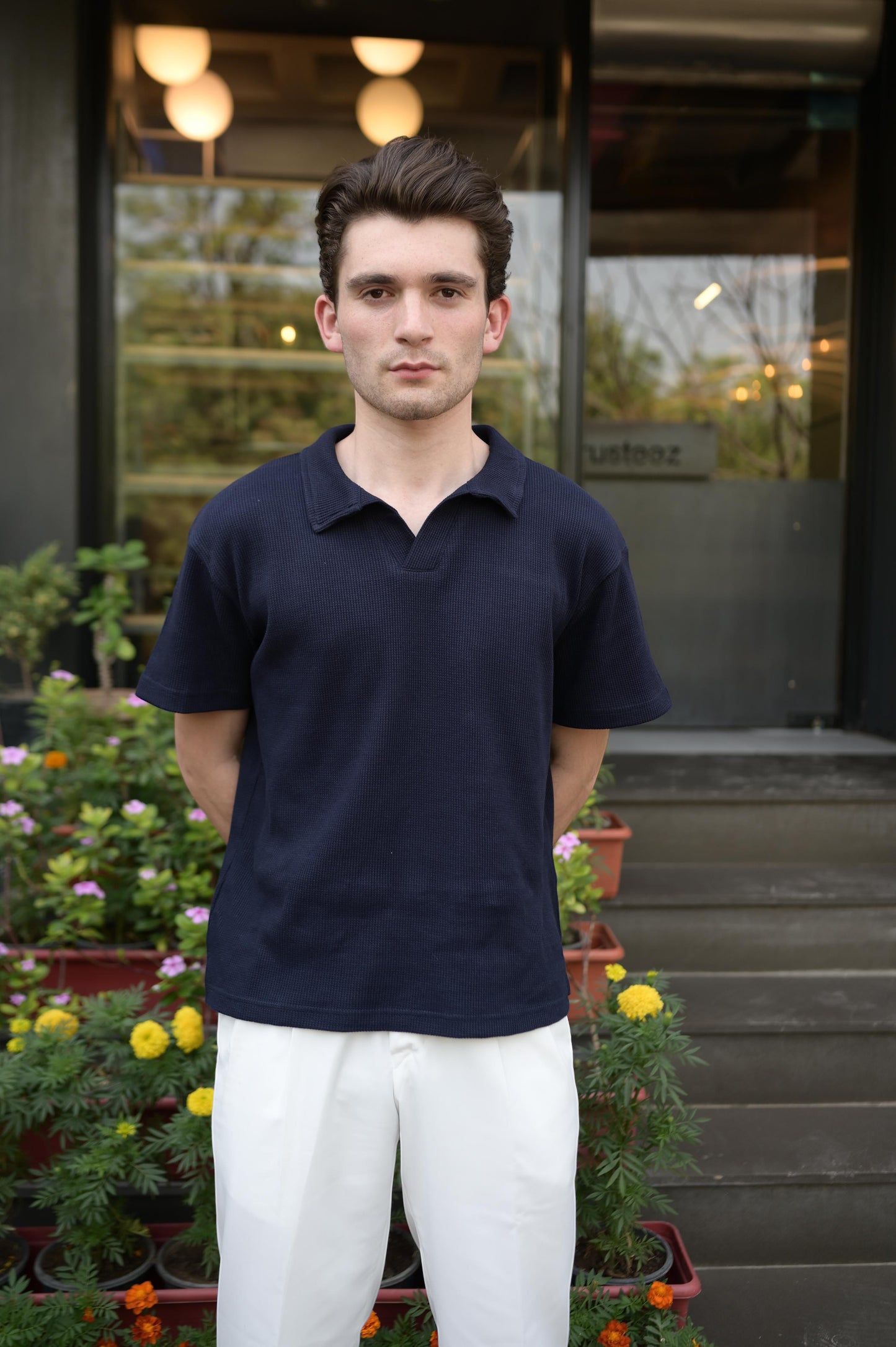 RADIUS midnight navy waffle-knit polo shirt with a V-neck and collar worn by a man with white trousers