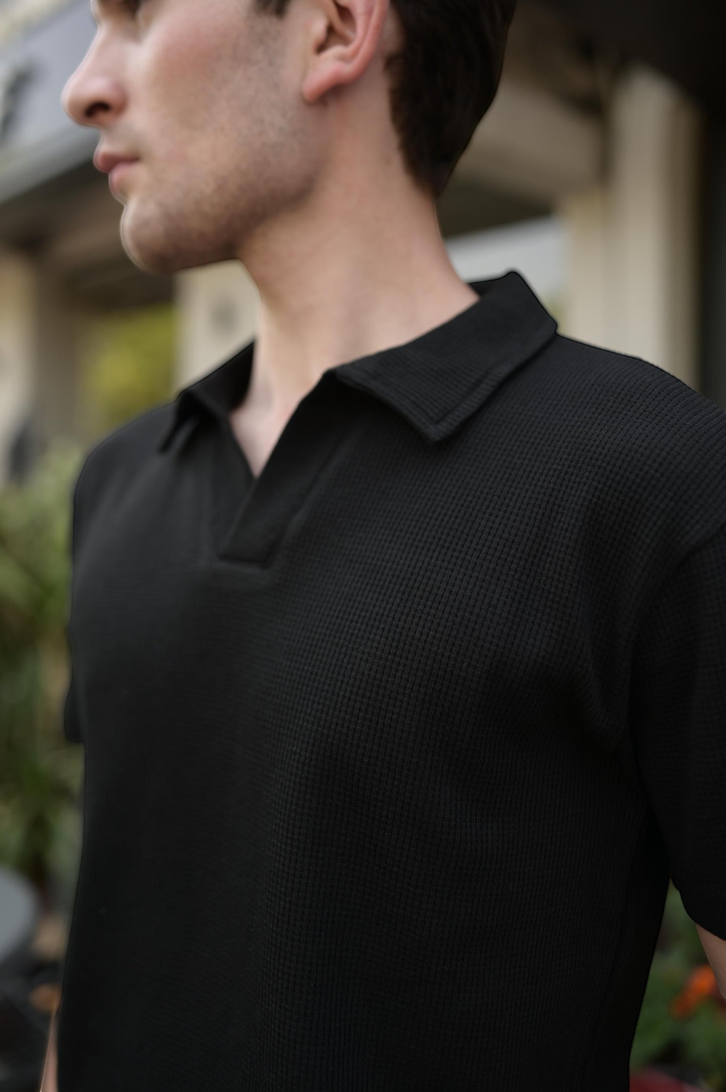RADIUS Obsidian black waffle-knit polo shirt with a minimalist V-neck collar and relaxed fit worn by a man.
