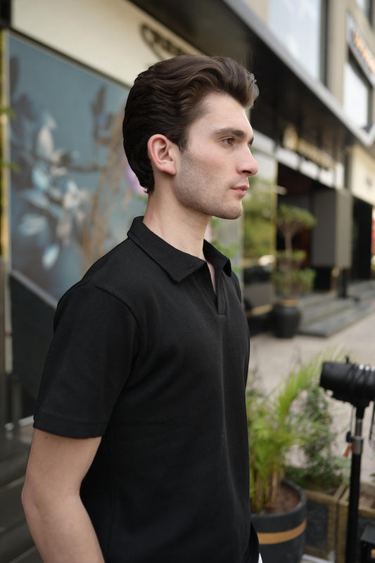 RADIUS Obsidian black waffle-knit polo shirt with a placket-less V-neck worn by a man outdoors.