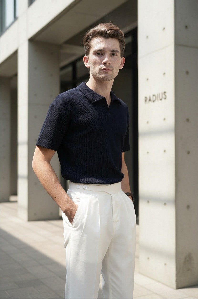 A man wearing RADIUS white Gurkha trousers with a navy polo shirt, featuring a dual-button waistband and front pleats.